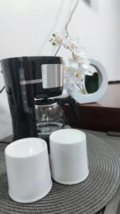 two white cups sitting on a table next to a coffee maker at Le Noci Room 2203 in Ao Nang Beach