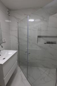 a white bathroom with a shower and a sink at ירושלים a in Safed