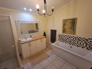 a bathroom with a sink and a tub and a mirror at Country Barns Guest house in Wakkerstroom