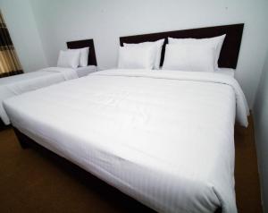 a large white bed with white sheets and pillows at BTI Leisure Hotel in Kataragama
