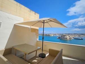 a table and chairs on a balcony with an umbrella at Portus Noir Valletta in Valletta