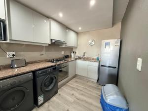 a small kitchen with a refrigerator and a dishwasher at Relaxing Blouberg Beachfront view Apartment in Cape Town