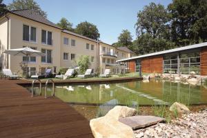 a pool in a yard with chairs and a building at Best Western Premier Park Hotel & Spa in Bad Lippspringe