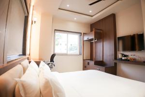 a bedroom with a white bed and a television at DHANUSH STAYS - A Boutique Accommodation in Varanasi +6 photos