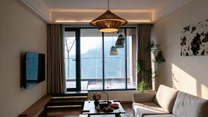 a living room with a couch and a large window at 重庆金佛山古核隐庐Resort Hotel in Nanchuan