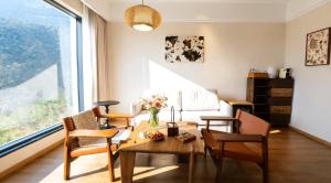 a living room with a table and chairs and a large window at 重庆金佛山古核隐庐Resort Hotel in Nanchuan