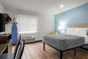 a hotel room with a bed and a television and a room at WoodSpring Suites Memphis East I-40 in Memphis