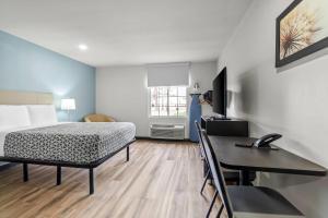 a bedroom with a bed and a desk and a table at WoodSpring Suites Memphis East I-40 in Memphis