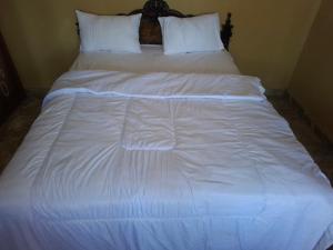a large white bed with white sheets and pillows at Amanda Ekas Homestay in Pulau Gilkaliantan