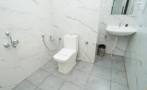 a white bathroom with a toilet and a sink at Hotel The Black Diamond in Bangalore