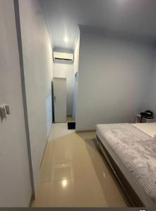 a white room with a bed and a hallway at Cherry Homestay in Kuta Lombok