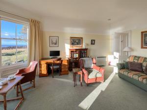 a living room with a couch and a table and a desk at Ruddon Grange in Elie