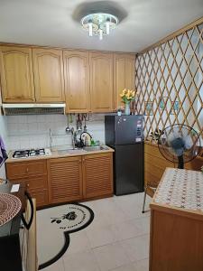 a kitchen with wooden cabinets and a black refrigerator at Riverbank 904 in Kuching