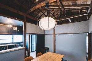 a dining room with a table and a light fixture at 松本市の静謐と温もりあふれる隠れ家邸宅 in Matsumoto