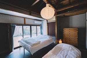 a bedroom with two beds and a large window at 松本市の静謐と温もりあふれる隠れ家邸宅 in Matsumoto