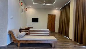 a living room with two benches and a tv at Hill View Resort - Kannur in Pālayangadi