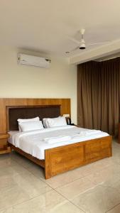 a bedroom with a large wooden bed with white sheets at Hill View Resort - Kannur in Pālayangadi