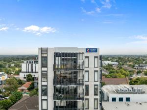 a tall white building with a sign on it at Comfort Apartments Box Hill in Box Hill