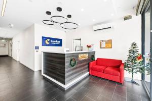 a lobby with a red chair and a christmas tree at Comfort Apartments Box Hill in Box Hill