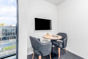 a room with a table and two chairs and a tv at Quality Apartments North Melbourne in Melbourne