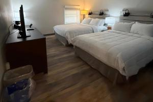 a hotel room with two beds and a flat screen tv at Clarion Pointe South Portland in South Portland
