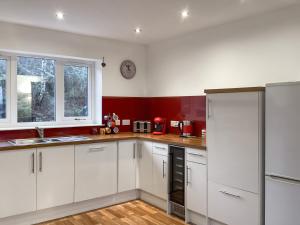 a kitchen with white cabinets and a clock on the wall at Shedfield Cottage in Drumnadrochit