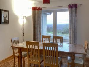 a dining room with a table and chairs and a window at Shedfield Cottage in Drumnadrochit