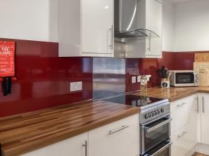 a kitchen with white cabinets and a stove top oven at Shedfield Cottage in Drumnadrochit