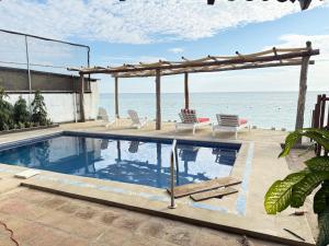 a swimming pool with chairs and a pergola next to the ocean at Casa villa del mar 2 in Miramar