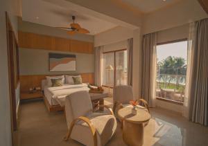 a hotel room with a bed and a table and chairs at Peninsula Del Mar Beach Resort in Udupi