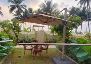 a table and chairs under an umbrella in a yard at Peninsula Del Mar Beach Resort in Udupi