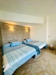two beds in a hotel room with blue pillows at Suite Acapulco vista al mar in Acapulco