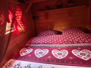a bed in a room with a red bedspread with hearts at Au Doubs Kota in Montlebon