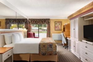 a hotel room with a bed and a desk and a television at Travelodge by Wyndham Owen Sound ON in Owen Sound