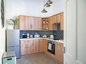 a small kitchen with wooden cabinets and appliances at Lovely Little Let in Birnam
