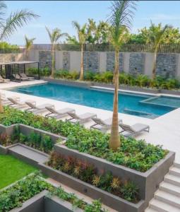 a swimming pool with lounge chairs and a palm tree at Urban Nook, The Bantree in Accra +7 photos