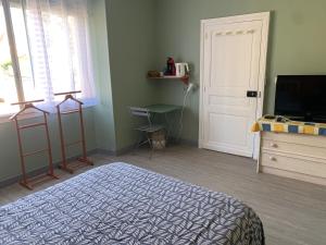 a bedroom with a bed and a television and a door at Chambre cosy avec salle de bain privée et piscine au calme in Saint-Sylvestre-sur-Lot