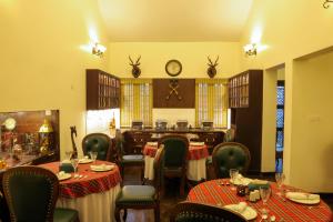 a restaurant with tables and chairs and a clock on the wall at Lynton Resorts in Kotagiri