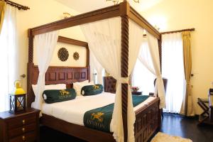a bedroom with a canopy bed with green pillows at Lynton Resorts in Kotagiri