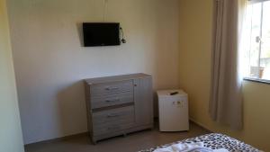 a bedroom with a dresser and a television on the wall at Pousada Viva Mar in Saquarema
