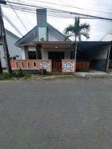 a house with a palm tree in front of it at Clara Guest House in Seturan