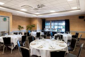 a room with white tables and chairs and a projection screen at Quality Hotel Lincoln Green in Auckland
