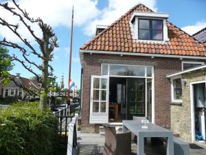 una casa de ladrillo con una mesa blanca delante de ella en Sonnehûs, en Hindeloopen