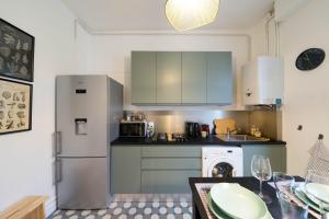 a kitchen with a stainless steel refrigerator and a table at AppartUnique - Chez Klein - Balcon, Lumineux & Spacieux in Vichy