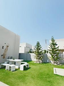 a patio with white tables and benches on grass at Nacha Pool Villa Cha-am in Cha Am