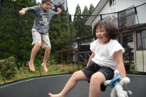 two young children jumping on a trampoline at Echoes of Forest エコーズオブフォレスト 森の音が聴こえるロッジ in Minamioguni