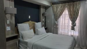 a bedroom with a large white bed with a window at The Palace in Pretoria