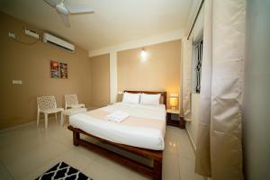 a bedroom with a bed and a table and chair at Aqua Wave by YogiTree Hotels in North goa