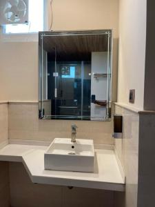 a bathroom with a white sink and a mirror at Hotel Tushar Elegant in Ghaziabad +20 photos