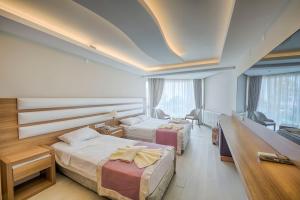 a hotel room with two beds and a television at RA Resort Otel in Küçükkuyu +55 photos